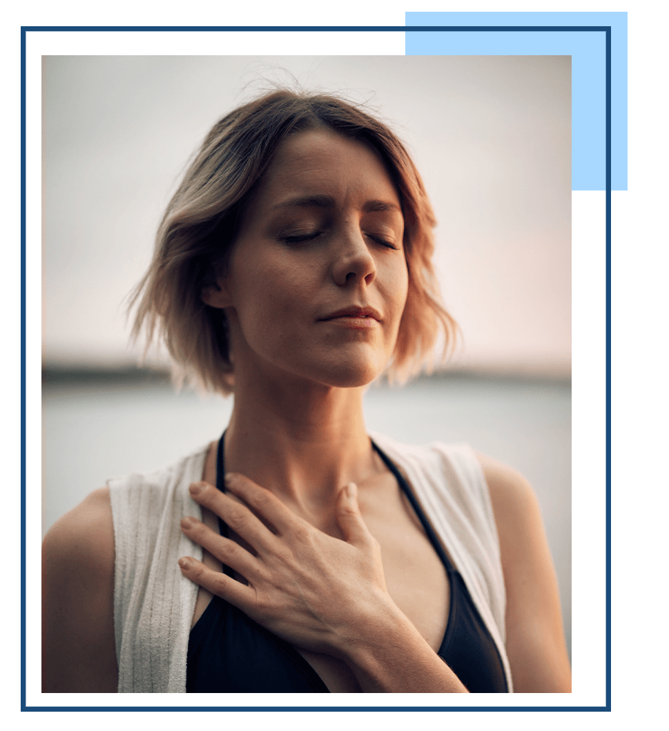 A woman breathing deeply with her eyes closed and hand on her chest