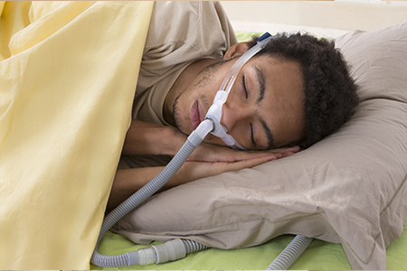 Man suffering of sleep apnea using a CPAP machine