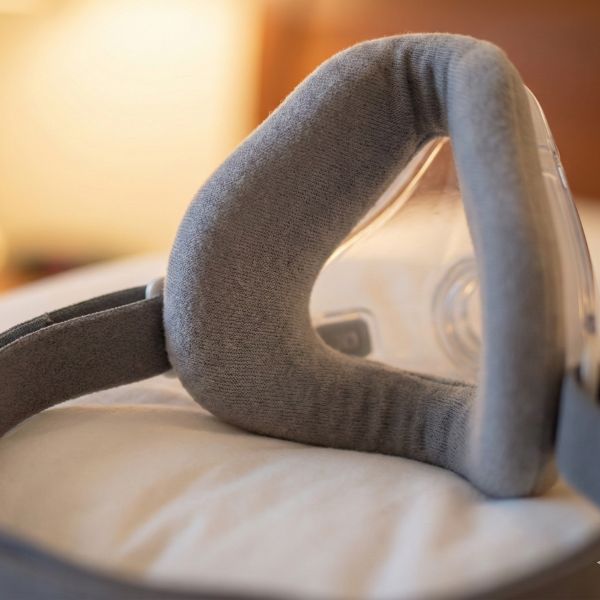 Sleep therapy mask fitted with a soft fabric comfort liner resting on a pillow